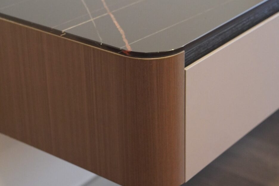 Close-up of a rounded wood-grain cabinet corner with a dark stone-look top